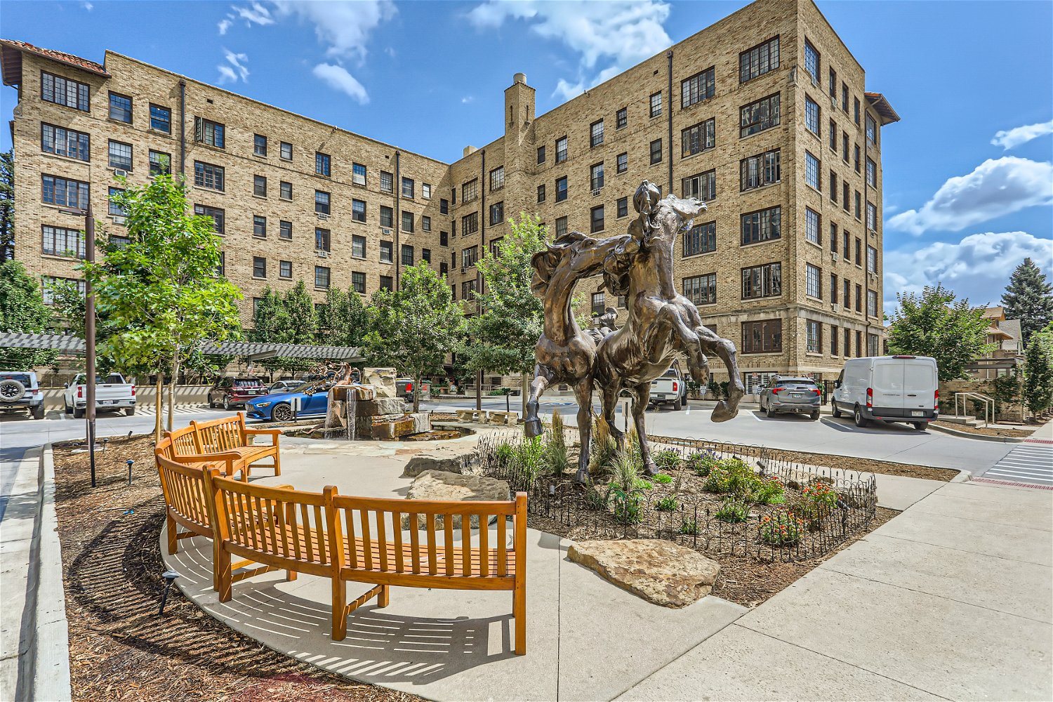 A statue of a horse is in the middle of a courtyard with benches around it.